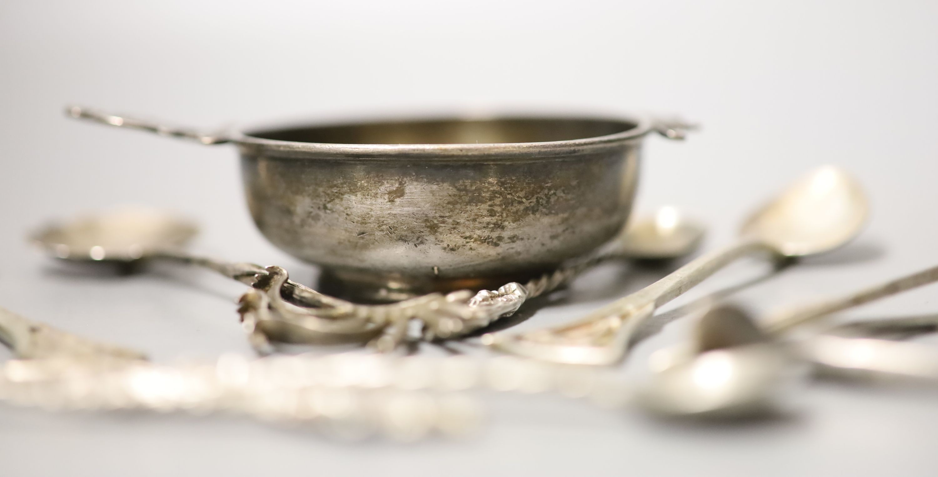 Small silver including two pairs of silver wishbone sugar nips, Levi & Salaman, Birmingham, 1922, a silver tea strainer and assorted spoons.